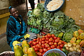 Einheimische fröhliche Frau an einem Obst- und Gemüsestand in der Markthalle, Lamu, Insel Lamu, Kenia, Afrika