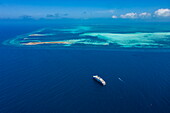 Luftaufnahme des Expeditionskreuzfahrtschiffes SH Diana (Swan Hellenic) und Riff vor der Insel Cosmoledo Atoll, Äußere Seychellen, Seychellen, Indischer Ozean