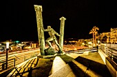  Statue of the Pillars of Hercules on the seafront of Ceuta at night in the background of the harbor, Ceuta, Strait of Gibraltar, Spain 