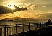 Abendstimmung am Europa Point, Paar beobachtet Sonnenuntergang über dem Meer, im Hintergrund die spanische Atlantikküste bei Tarifa, Gibraltar, Britische Kronkolonie, Iberische Halbinsel