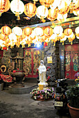  Unexpected discovery in the backyard: The goddess in the lotus blossom, Quan Yin, stands next to a parked scooter and is illuminated by numerous lanterns. Taipei, Taiwan 