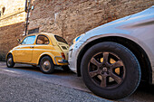  small Fiat 500 stands next to large SUV car, Siena, Tuscany region, Italy, Europe 