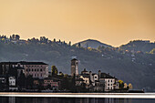 Blick auf Isola San Giulio vom Hafen in Pella bei Sonnenaufgang, Westufer des Ortasees, Ortasee Lago d’Orta, Provinz Novara, Region Piemont, Italien
