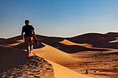  Africa, Morocco, Zagora, Sahara, Erg Lehoudi, man walking over sand dune 