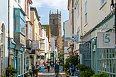 Shops in historic buildings along alleyway with tower of church of St Saviour, Foss Street, Dartmouth, Devon, England, UK