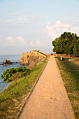Touristen spazieren auf den Festungswällen in der historischen Stadt Galle, Sri Lanka, Asien