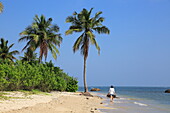 Woman walking on sandy tropical beach at Pasikudah Bay, Eastern Province, Sri Lanka, Asia