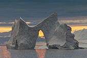 Eisberg mit Torbogen im Sonnenuntergang, Kangia Eisfjord, UNESCO Weltnaturerbe, Disko-Bucht, West-Groenland, Grönland