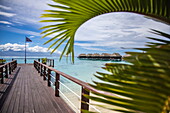 Pier und Overwater-Bungalows des Sofitel Ia Ora Beach Resort, gesehen durch Palmwedel, Moorea, Windward Islands, Französisch-Polynesien, Südpazifik