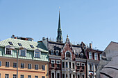  House facades in the old town, behind them the top of St. Peter&#39;s Church, Riga, Latvia 