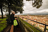 Turist admires the view, city center seen from above, Lucca medioeval city, Tuscany, Italy
