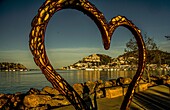  Port d´Andratx, seen in the morning light through the heart-shaped sculpture &quot;Thierro&quot; by Carlos Terroba, Mallorca, Spain 