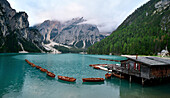 Pragser Wildsee am frühen Morgen, Bootshütte auf Pfählen, aufgereihte Ruderboote, Marienkapelle am Rand des Bergsees. Dolomiten, Südtirol, Italien, Europa