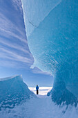  Tourist at iceberg in Fjallsarlon glacier lagoon, winter, Iceland 