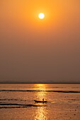 Silhouette eines Kanus auf dem Fluss Dakatiya bei Sonnenuntergang, Chandpur, Distrikt Chandpur, Bangladesch, Asien