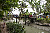  Passengers of river cruise ship RV Thurgau Ganga Vilas (Thurgau Travel) and children crossing footbridge in Kumar Pada village (potters&#39; colony), Kaukhali (Kawkhali), Pirojpur District, Bangladesh, Asia 