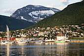 Suburban housing and landscape of snow on mountain side, Tromso, Norway warm evening light