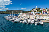 Blick auf Segelboote und Yachten am Pier mit Ort und Uhrenturm auf Hügel, Insel Poros, Attika, Peloponnes, Ägäis, Griechenland, Europa