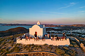  Aerial view of people enjoying the sunset from Panagia Church at Plaka Castle, Plaka, Milos, South Aegean, Greece, Europe 