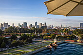  Couple in the rooftop infinity pool of Glow Park Hotel overlooking the Royal Palace and city skyline, Phnom Penh, Phnom Penh, Cambodia, Asia 