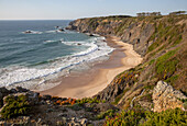Secluded sandy beach in bay between rocky headlands at Parque Natural do Sudoeste Alentejano e Costa Vicentina, Natural Park, landscape view on the Ruta Vicentina long distance walking trail, at Praia dos Machados,  Carvalhal, Alentejo Littoral, Portugal, southern Europe