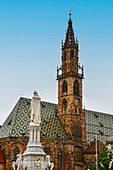  Cathedral of the Assumption of Mary in Bolzano, bell tower and roof with diamond pattern, marble sculpture by Walther von der Vogelweide. Bolzano, South Tyrol, Trentino, Italy, Europe 