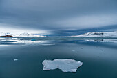 Blick auf türkise  Eissschollen und schneebedeckte Berge  im Isfjord von Spitzbergen, Svalbard, Norwegen, Arktis