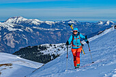  Woman on ski tour ascending to Standkopf, Guffert in the background, Standkopf, Kitzbühel Alps, Tyrol, Austria 