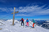  Three people on ski tour standing on the summit of Torhelm, Torhelm, Langer Grund, Kelchsau, Kitzbühel Alps, Tyrol, Austria 