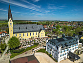  Woman cycling through Bernau with view of church and Bonnschlössl, Bernau, Lake Constance-Königssee cycle path, Upper Bavaria, Bavaria, Germany 