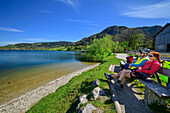 Mann und Frau auf dem Bodensee-Königssee-Radweg sitzen am Schliersee und machen Pause, Schliersee, Oberbayern, Bayern, Deutschland