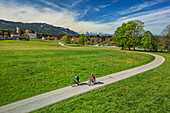Mann und Frau fahren auf dem Bodensee-Königssee-Radweg mit Wieskirche im Hintergrund, Wies, UNESCO Welterbe Wieskirche, Oberbayern, Bayern, Deutschland