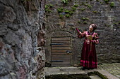  Woman in costume of the “Lady-in-waiting from Kassel”, character from the fairy tale by the Brothers Grimm, explains historical city wall in the old town, Steinau an der Straße, Spessart-Mainland, Hesse, Germany 