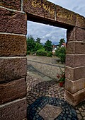 View through an arch onto the fairytale square, in the background bust of Dorothea Viehmann, fairytale district Niederzwehren, Kassel, Hesse, Germany 