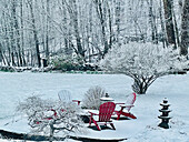 Snowy patio and landscape with red Adirondack chairs