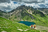  Man and woman hiking looking at Eisbruggsee, Eisbruggsee, Pfunderer Höhenweg, Zillertal Alps, South Tyrol, Italy 