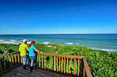  Man and woman hiking standing at viewing platform and looking out to sea, Alexandria Hiking Trail, Addo Elephant National Park, Eastern Cape, South Africa 