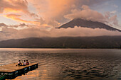 Tourists on a mooring enjoying the sunset, Lake Atitlan and San Pedro volcano, Santiago Atitlan, Sololá department, Guatemala