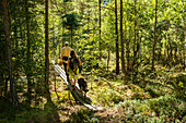 Junges kaukasisches Paar mit Hund läuft über einen Holzsteg in Listorp, einem Naturschutzgebiet in Südschweden