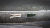  2 rowing boats lie motionless on the sea. Light fog. Reflection in the water. Loch Morlich, Highlands, Scotland, Great Britain 