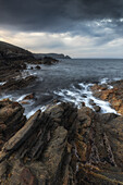  Rocky coast at Burravoe. Dark rain clouds. 