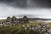  A dilapidated cottage with remains of walls stands in a lonely landscape on Shetland. Dark sky. 