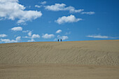 epic view of 2 people walking on the sand dune