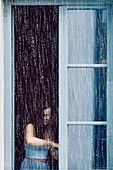  Girl at window behind pouring rain in Munich, Bavaria, Germany 