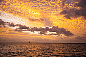 Silhouette eines Segelboots und Wolken bei Sonnenuntergang über dem Meer, Trou aux Biches, Pamplemousses, Insel Mauritius, Indischer Ozean