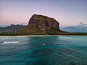  Aerial view of waves breaking on reef at dusk with lagoon and Le Morne mountain at dusk, Le Morne, Rivière Noire, Mauritius, Indian Ocean 