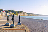 Bronzestatuen von drei Mädchen unter dem Titel "L'heure du bain" von Dominique Denry am Strand und und Ausblick auf die Kreidefelsen bei Sonnenuntergang in Fécamp (Fecamp) an der Alabasterküste (Côte d'Albâtre, Cote d'Albatre) im Département Seine-Maritime in der Region Normandie in Frankreich