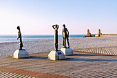 Bronzestatuen von drei Mädchen unter dem Titel "L'heure du bain" von Dominique Denry am Strand und Blick auf die Hafeneinfahrt bei Sonnenuntergang in Fécamp (Fecamp) an der Alabasterküste (Côte d'Albâtre, Cote d'Albatre) im Département Seine-Maritime in der Region Normandie in Frankreich