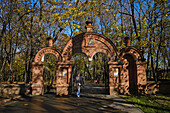  Frau geht an einem sonnigen Herbsttag durch ein Kirchentor im Museumsreservat Kolomenskoje. Moskau, Russland. 