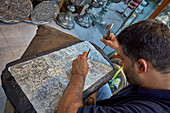 Qalamzani, or Ghalamzani (traditional Iranian metal engraving art) artist works in a handicraft store. Isfahan, Iran.